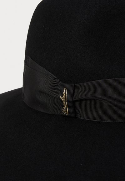 Chapeau en feutre noir avec un bandeau en ruban noir lisse et un accent doré signature. Le design est arrondi avec une texture douce.