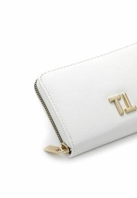 White textured wallet with gold hardware, featuring a zip closure and embossed "TL" logo in a modern, minimalist design.