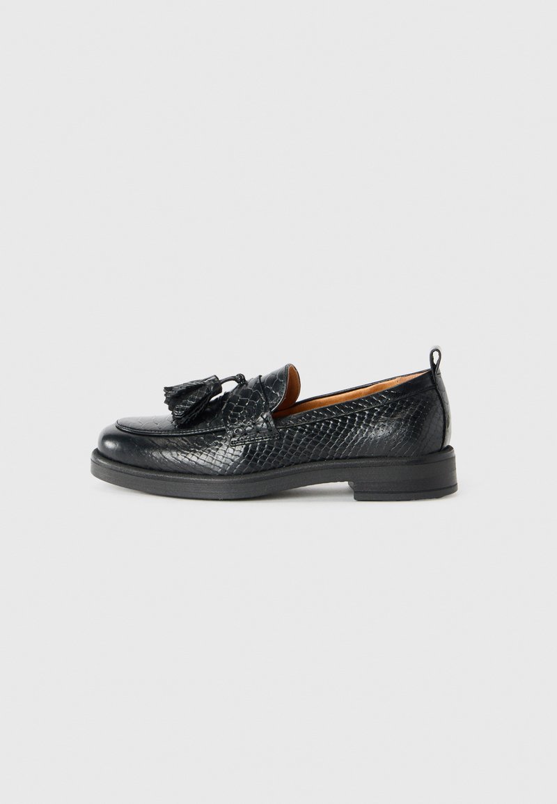 Black leather loafers with a textured pattern and tassels on top, featuring a low heel and pull tab at the back.