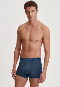 Marineblauwe heren boxershorts met een zachte, gladde textuur en een aansluitend ontwerp. Beschikt over een merkgebonden elastische tailleband zonder zichtbare naden.