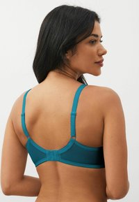 Teal bh met verstelbare bandjes, een gladde textuur en een haak-en-oogsluiting op de rug, met een subtiele geschulpte randafwerking.