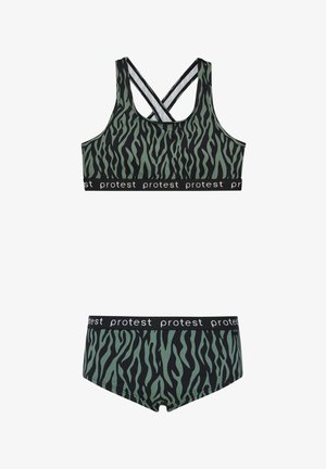 Zelena i crna sportska brusa sa uzorkom zebre s križastim naramenicama i crnim elastičnim trakom koji sadrži ponavljajući bijeli tekst. Uključene su i odgovarajuće gaćice.