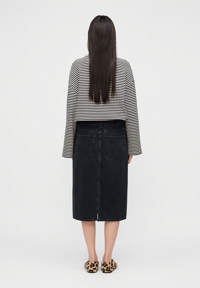 Μαύρη τζιν μίντι φούστα με ίσια γραμμή και πίσω τσέπες, συνδυασμένη με κοντό πλεκτό πουλόβερ σε μαύρο και λευκό ριγέ και παπούτσια με λεοπάρ μοτίβο.