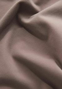 Tissu doux et texturé de couleur brune atténuée, présentant de douces plis et une surface lisse, idéal pour diverses applications textiles.