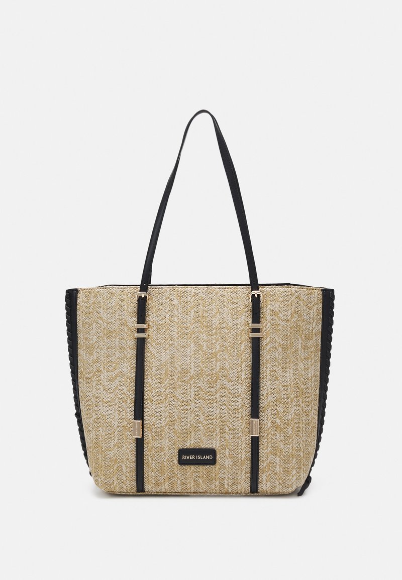 Beige woven tote bag with black accents, features two handles, gold-tone hardware, and a textured pattern on the surface.