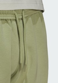 Pantalones de chándal verde claro con cintura ajustable, que cuentan con una tela texturizada y dos bolsillos laterales. La cinturilla es acanalada para mayor comodidad.