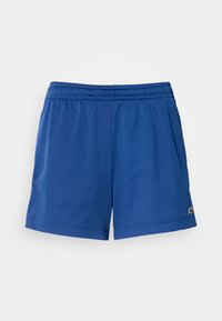 Calções atléticos azuis feitos de tecido leve com um cós elástico, apresentando bolsos laterais e um pequeno logotipo perto da bainha.