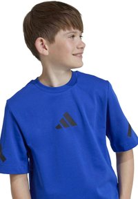 Camiseta de manga corta azul, hecha de un tejido suave, con acentos de logotipo triangular negro en el frente y en las mangas.