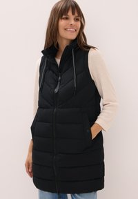 Schwarze Daunenweste mit Reißverschluss, Kapuze und verstellbaren Kordeln. Verfügt über Seitentaschen und ein gestepptes Design. Leicht und warm.