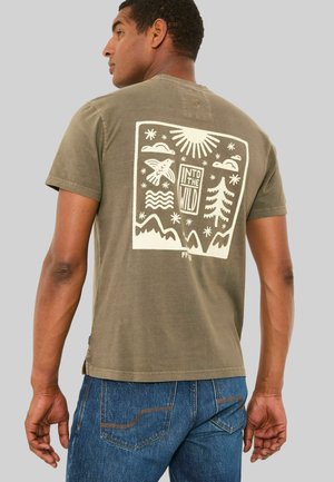 Olivegrünes Baumwoll-T-Shirt mit einem großen weißen Grafikdruck auf der Rückseite, der Naturmotive wie Berge, Bäume und einen Vogel zeigt.