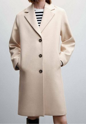 Beige wollen jas met een getailleerd ontwerp, voorzien van een gelapte revers, drie donkergekleurde knopen en zijzakken. Soepele textuur, knielange snit.
