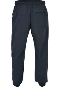 Pantalone od tamnoplave elastične tkanine s bočnim džepovima, sužene nogavice i rebrastim manžetama. Napravljeni od lagane tkanine s glatkom teksturom.