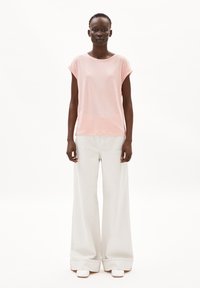 Ljusrosa topp med kort ärm som matchas med vida ljusgrå byxor och vita slip-in skor; mjukt tyg och avslappnad passform.