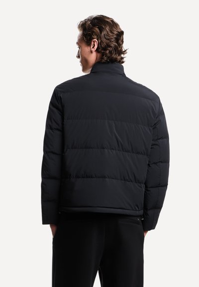 Zwarte pufferjack met een hoge kraag, een gewatteerd ontwerp en elastische manchetten. Zachte, gladde textuur met verborgen zijzakken.