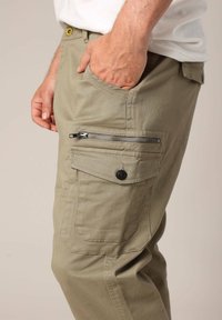 Khaki cargobroeken met een ritssluiting zijzak, voorzakken en een knoopsluiting. De stof lijkt stevig met een gladde textuur.