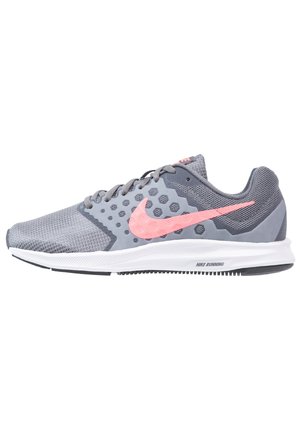 Grijze en roze Nike hardloopschoen met een bovenwerk van mesh, zeshoekig patroon, roze swoosh-logo en witte zool tegen een witte achtergrond.