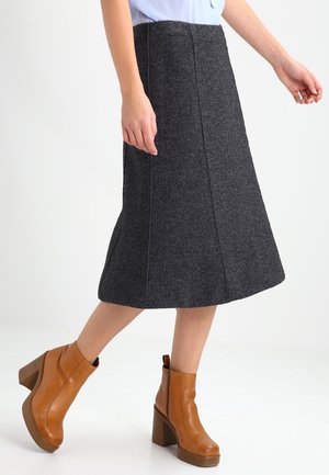 Grijze A-lijn wollen rok met zichtbare naden en een knielange snit, gecombineerd met tan enkellaarzen met een dikke hak en zijrits.