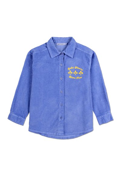 Camicia in corduroy blu con design a bottoni, maniche lunghe e grafica di un fiore giallo con la scritta "Divertiti". Tessuto a coste molto evidente.