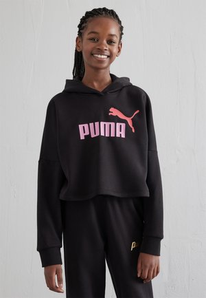 Hanorac scurt, negru, dintr-un material moale, având un logo roz "PUMA" proeminent și o siluetă mică de puma roz. Acesta este asortat cu pantaloni negri.