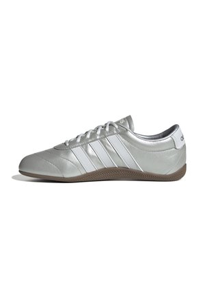 Scarpa sportiva argento con tre strisce bianche, punta tonda, design con lacci, texture in pelle liscia e suola in gomma marrone.