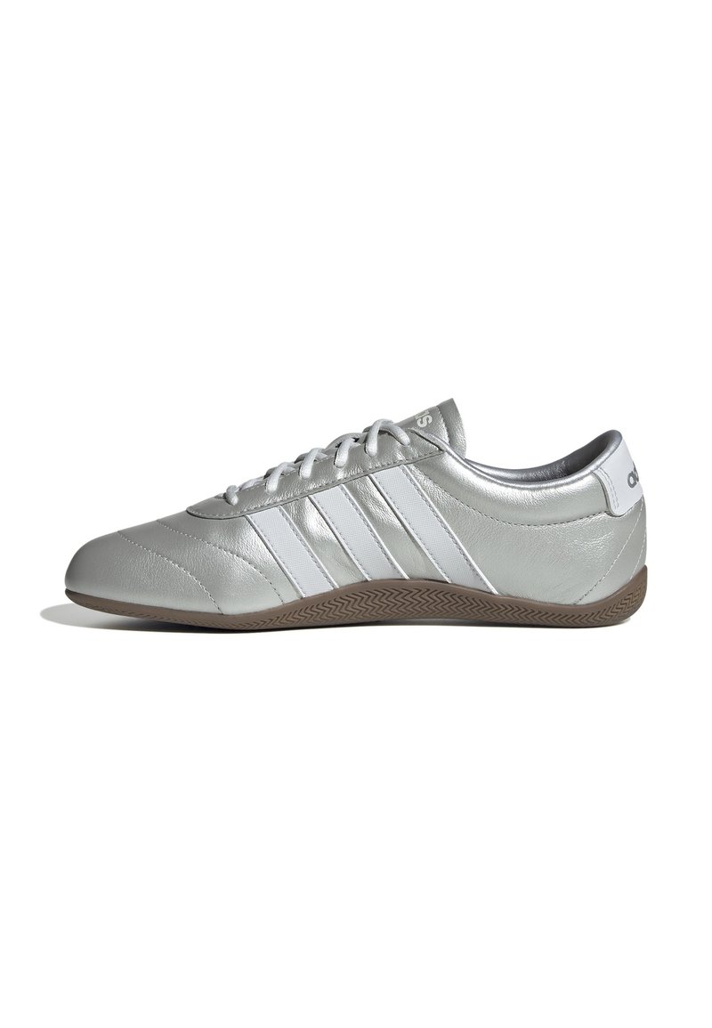 Scarpa sportiva argento con tre strisce bianche, punta tonda, design con lacci, texture in pelle liscia e suola in gomma marrone.