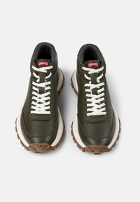 Grüne Leder-Sneaker mit weißen Schnürsenkeln, einem gepolsterten Kragen und einer klobigen braunen Gummisohle; enthält ein rotes Markenetikett auf der Zunge.