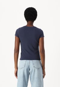 Maglietta aderente blu navy con maniche corte, realizzata in morbido cotone, caratterizzata da un collo rotondo classico e una texture liscia, senza decorazioni.