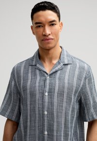 Korte mouw knoopshirt in gestructureerde grijze stof met dunne witte strepen, met een camp collar en kleine knopen.