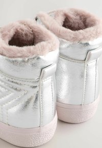 Silberne und pinke Knöchelstiefel mit metallischem Finish, ausgestattet mit einem plüschigen pinken Kunstfellfutter und strukturierten Gummisohlen.
