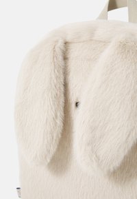 Cream-colored plush backpack featuring prominent long, floppy bunny ears and a soft fur texture. Notable details include a small black nose.