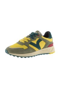 Zapatilla multicolor con paneles en amarillo, verde y verde azulado, parte superior de ante y malla, y suela exterior de goma texturizada con agarre.