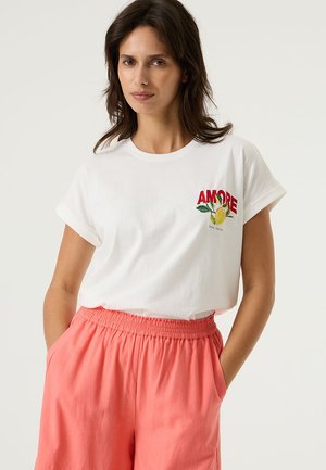Wit katoenen t-shirt met opgerolde mouwen, voorzien van rode "AMORE" borduursel en citroengrafiek, gecombineerd met roze short met elastische taille.