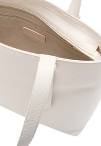 Sac fourre-tout en cuir blanc avec une texture extérieure, ouverture sur le dessus et doublure intérieure discrète. Doté d'une fermeture éclair dorée et d'une étiquette de marque.