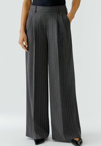 Pantalons larges gris foncé avec des rayures verticales. Dispose d'une taille cintrée et de deux poches latérales, fabriqués à partir d'un tissu texturé.
