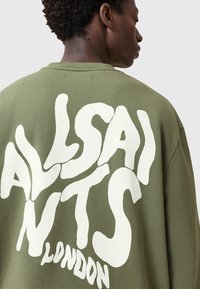 Felpa in verde oliva con il testo stilizzato e in bianco "ALLSAINTS LONDON" sul retro. Realizzata in morbido cotone con una vestibilità comoda.