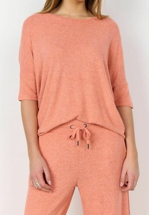 Haut ample de couleur pêche avec un col rond et des manches courtes, en tissu doux, assorti à un pantalon à cordon de serrage.
