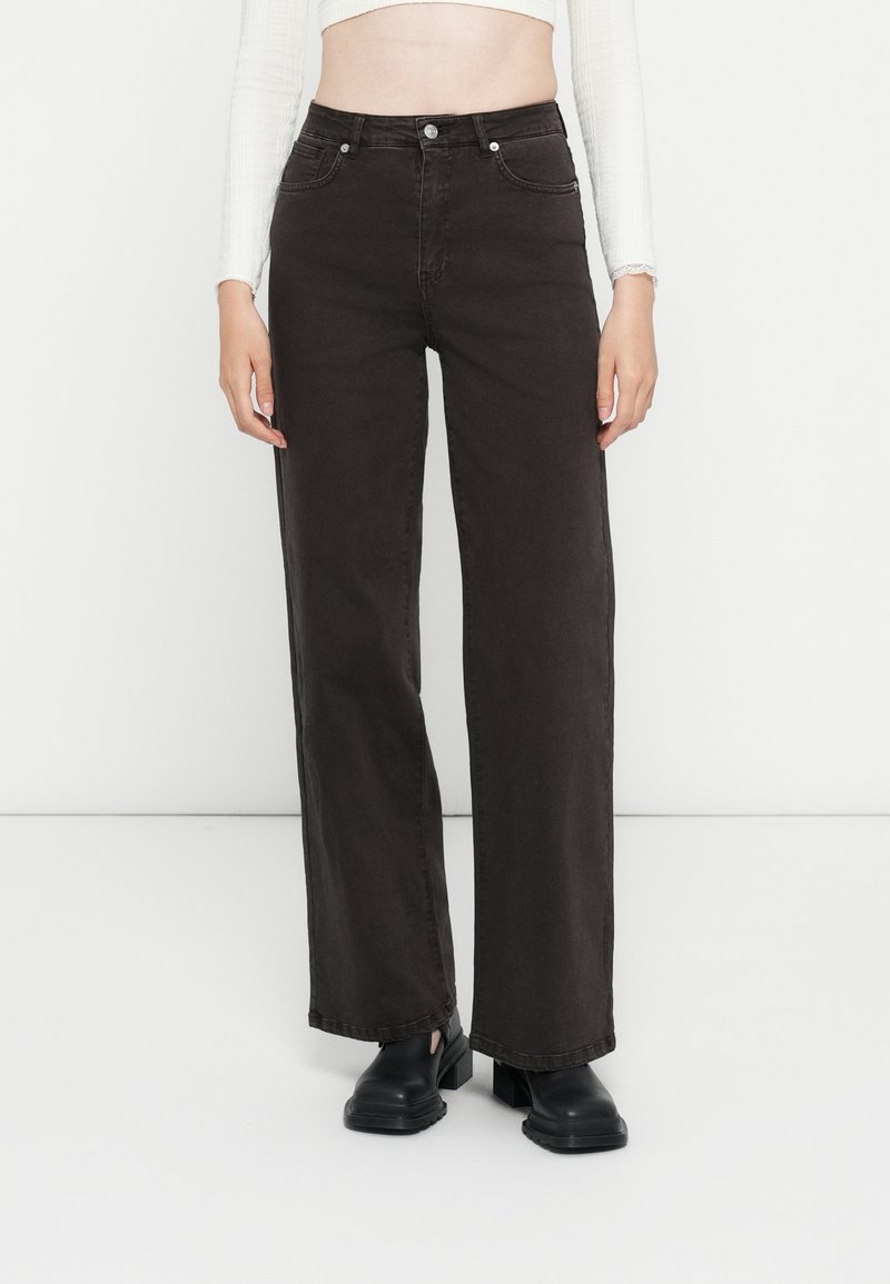 Donkerbruine wijde jeans met hoge taille, twee voorzakken en rafelrand. De stof heeft een gladde textuur met een lichte glans.
