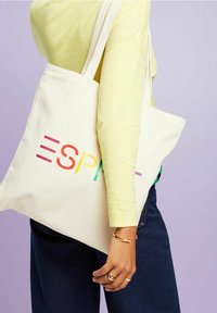 Cremefarbener Canvas-Shopper mit buntem "ESPRIT"-Logo. Verfügt über zwei Schultertragegurte und ein einfaches, schmuckloses Design.