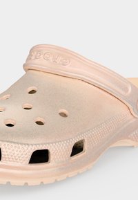 Ανοιχτό ροζ clog Crocs με οπές αερισμού και υφασμένο λουράκι με το λογότυπο Crocs.