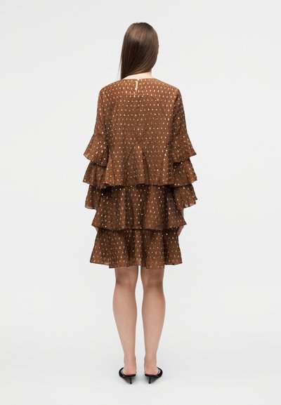 Robe marron à volants avec col rond, manches à volants, motif à pois blancs et détail de dos à découpe en goutte d'eau. Texture lisse, longueur au-dessus du genou.