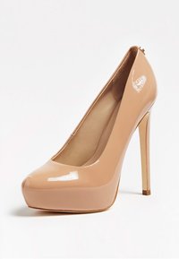 Escarpin à talon haut en cuir verni beige avec bout arrondi et talon aiguille sur fond blanc.