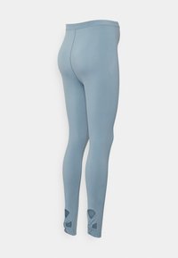 Leggings azul claro feitos de material elástico, com recortes atados nos tornozelos e uma cintura larga e lisa.