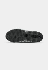 Black rubber outsole with textured grooves, featuring a contrasting grey midsole and a circular cutout. Durable construction for traction.