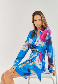 Bright blue dress with pink and yellow abstract patterns; long sleeves, belted waist, smooth fabric, knee-length design.