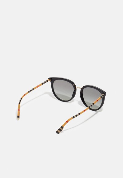 Óculos de sol pretos com lentes de tonalidade cinza. As hastes apresentam um padrão riscado em laranja, preto e bege. Detalhes em tom dourado.
