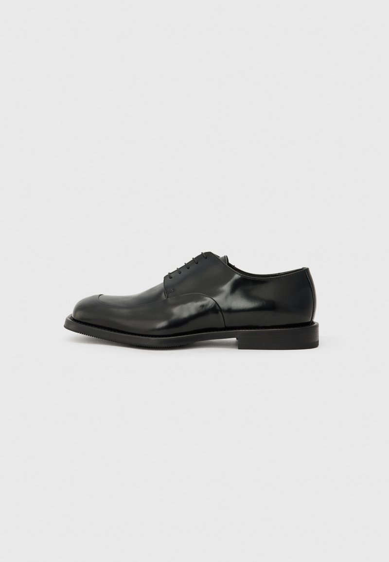 Black leather dress shoe with a polished finish, rounded toe, five lace eyelets, and a flat rubber sole. Smooth texture with minimal accents.