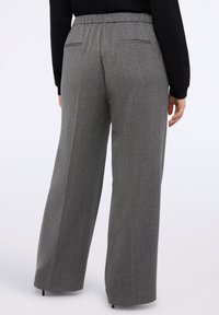 Šedé kalhoty s širokými nohavicemi z texturované látky, mají elastický pas a dvě zadní kapsy. Minimalistický design, žádné viditelné vzory.