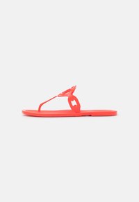 Korallfärgade gummitofflor med en smal rem och dekorativ blomdetalj. Platt sula, lättviktig design, lämplig för avslappnad användning.