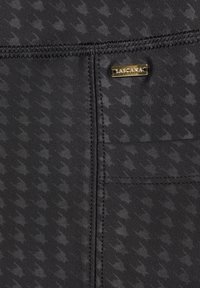 Zwart sportstof met een houndstooth patroon en een gladde textuur. Een gouden merklabel is bevestigd nabij een naad.