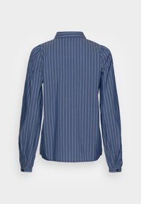 Camicia a maniche lunghe blu a righe con colletto classico, righe bianche verticali e polsini con bottoni con dettagli arricciati sulle maniche.